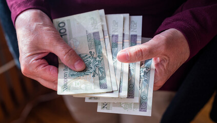 pensioner woman holding in her hands money bills zloty pension and pennies for payment
