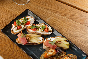 Bruschettas with vegetables. Start dishes with cherry tomatoes, avocado, cream cheese and shrimps. Food composition, tasty italian meal