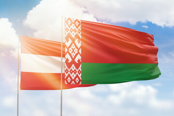 Sunny blue sky and flags of belarus and austria