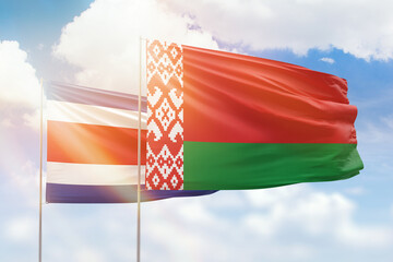 Sunny blue sky and flags of belarus and costa rica