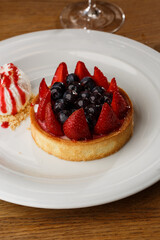 Berry tartlets with curd cream on a wooden background. Summer fruit baking. Tartlets with raspberries, blueberries and red currants. Served with ice cream.