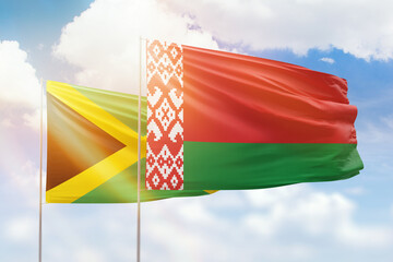 Sunny blue sky and flags of belarus and jamaica