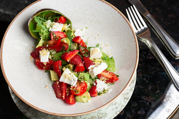 Tasty and healthy salad with arugula, brie cheese, avocado, cherry tomatoes and strawberry. Top view. The flat lay. Banner