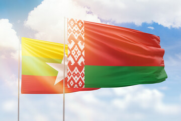 Sunny blue sky and flags of belarus and myanmar