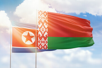 Sunny blue sky and flags of belarus and north korea