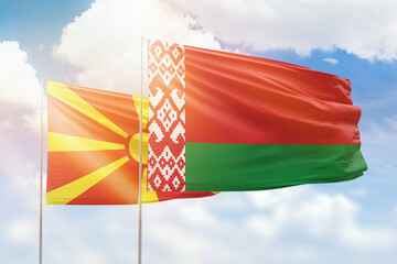 Sunny blue sky and flags of belarus and north macedonia