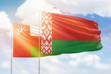 Sunny blue sky and flags of belarus and oman