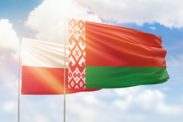 Sunny blue sky and flags of belarus and poland