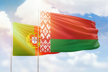 Sunny blue sky and flags of belarus and portugal