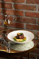 Grilled meat fillet steak medallion with green sauce, served with pear or apple. On dark background