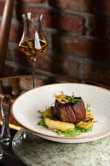 Grilled meat fillet steak medallion with green sauce, served with pear or apple. On dark background