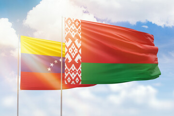 Sunny blue sky and flags of belarus and venezuela