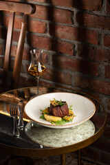 Grilled meat fillet steak medallion with green sauce, served with pear or apple. On dark background