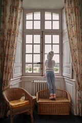 Little girl standing at the sofa and looking at the window after the shower