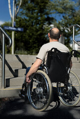 Fototapeta na wymiar Rollstuhlfahrer mit Rollstuhl steht vor Treppe am Bahnsteig, Mobilität barrierefrei behindertengerecht Beeinträchtigung Inklusion