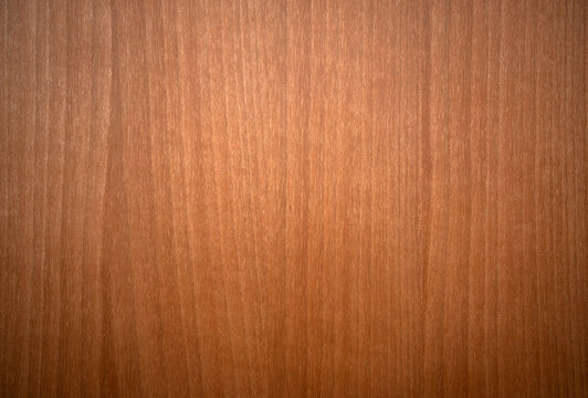 Photo of a tree texture with vertical lines.Mahogany wooden background. Orange background made of wood veneer in the style of the 70s.