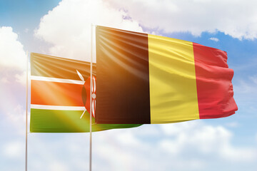 Sunny blue sky and flags of belgium and kenya