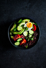 Black rice salad with vegetables, avocado, egg and spring onion
