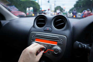 Hand to adjust the volume knob of the car's music player, car parking on the road