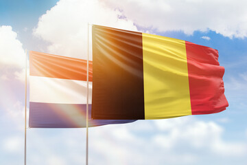Sunny blue sky and flags of belgium and netherlands