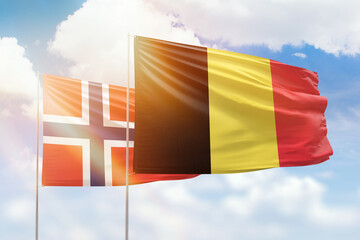 Sunny blue sky and flags of belgium and norway