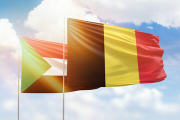 Sunny blue sky and flags of belgium and sudan
