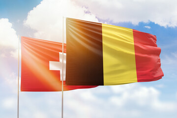 Sunny blue sky and flags of belgium and switzerland
