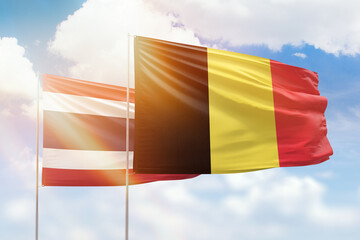 Sunny blue sky and flags of belgium and thailand