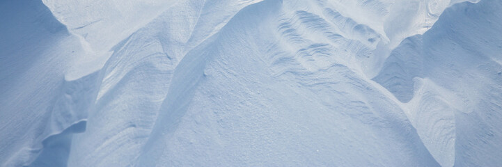 Beautiful winter background with snowy ground. Natural snow texture. Wind sculpted patterns on snow surface. Arctic, Polar region.