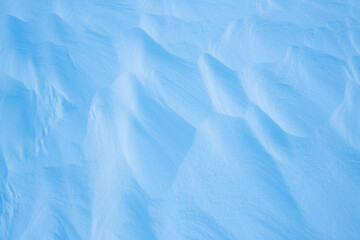 Beautiful winter background with snowy ground. Natural snow texture. Wind sculpted patterns on snow surface.