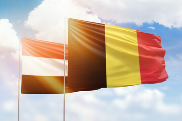 Sunny blue sky and flags of belgium and yemen