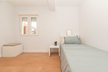 Fototapeta na wymiar Bedroom with a youth bed with a blue bedspread, white furniture, an aluminum window and a light wooden floor