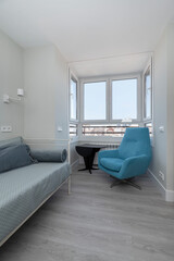 Corner of a room with a blue individual rest sofa, gazebo with views and gray parquet floors
