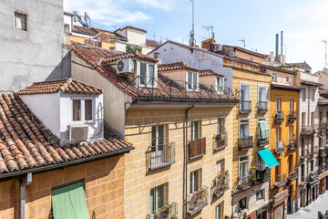Facades of old buildings with roofs and attics and balconies with metal railings in a street in the center of Madrid's La Latina neighborhood