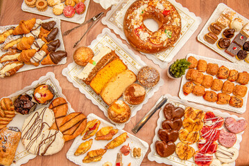 Set of plates with desserts, chocolate palm trees, sweet and savory filled croissants, sponge cakes of various flavors, savory snacks, assorted cupcakes and a roscon with whipped cream