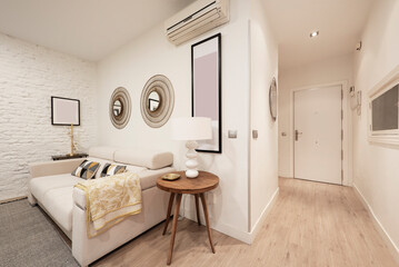 Hallway and living room with white fabric sofa and round wooden side table in vacation rental home