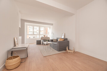 Fototapeta na wymiar Apartment living room with window, gray three-seater sofa and wooden floors