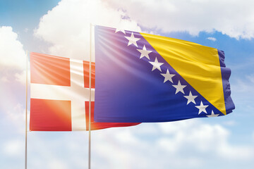 Sunny blue sky and flags of bosnia and denmark