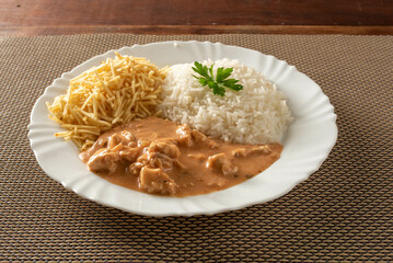 Chicken stroganoff accompanied with rice, salad and potato straw.