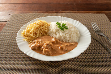 Chicken stroganoff accompanied with rice, salad and potato straw.