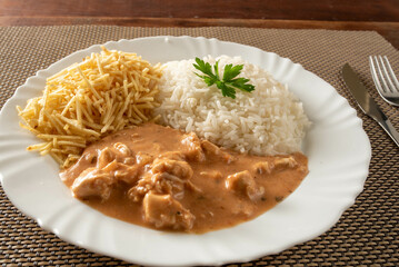 Chicken stroganoff accompanied with rice, salad and potato straw.