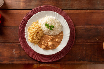 Chicken stroganoff accompanied with rice, salad and potato straw.