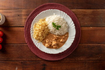 Chicken stroganoff accompanied with rice, salad and potato straw.