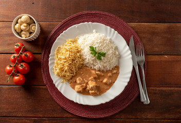 Chicken stroganoff accompanied with rice, salad and potato straw.