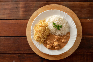 Chicken stroganoff accompanied with rice, salad and potato straw.