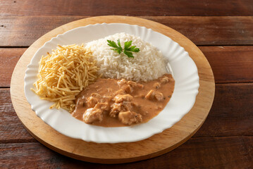 Chicken stroganoff accompanied with rice, salad and potato straw.