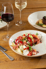 Prosciutto crudo ham salad with mozzarella cheese and arugula on a plate. Bright background. Top view. Copy space