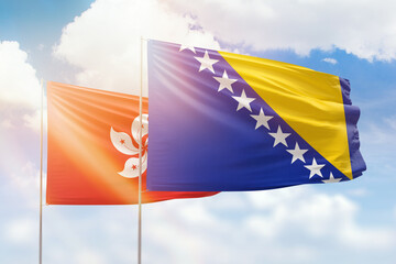 Sunny blue sky and flags of bosnia and hong kong