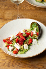 Tasty and healthy salad with arugula, brie cheese, avocado, cherry tomatoes and strawberry. Top view. The flat lay. Banner