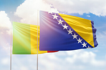 Sunny blue sky and flags of bosnia and mali